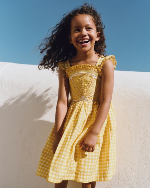 A girl wearing a yellow gingham dress.