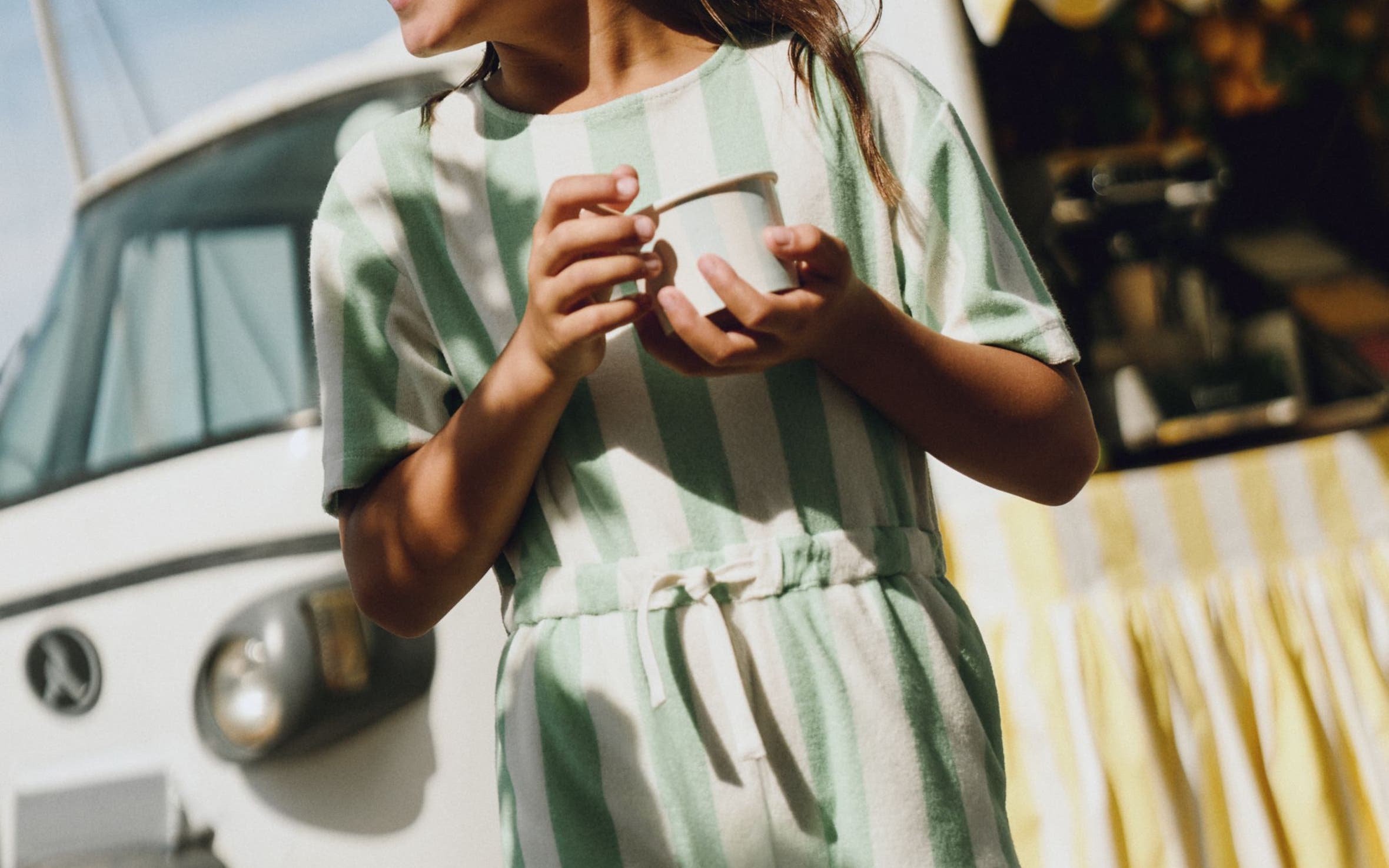 A girl wearing a striped romper from Mini Boden.