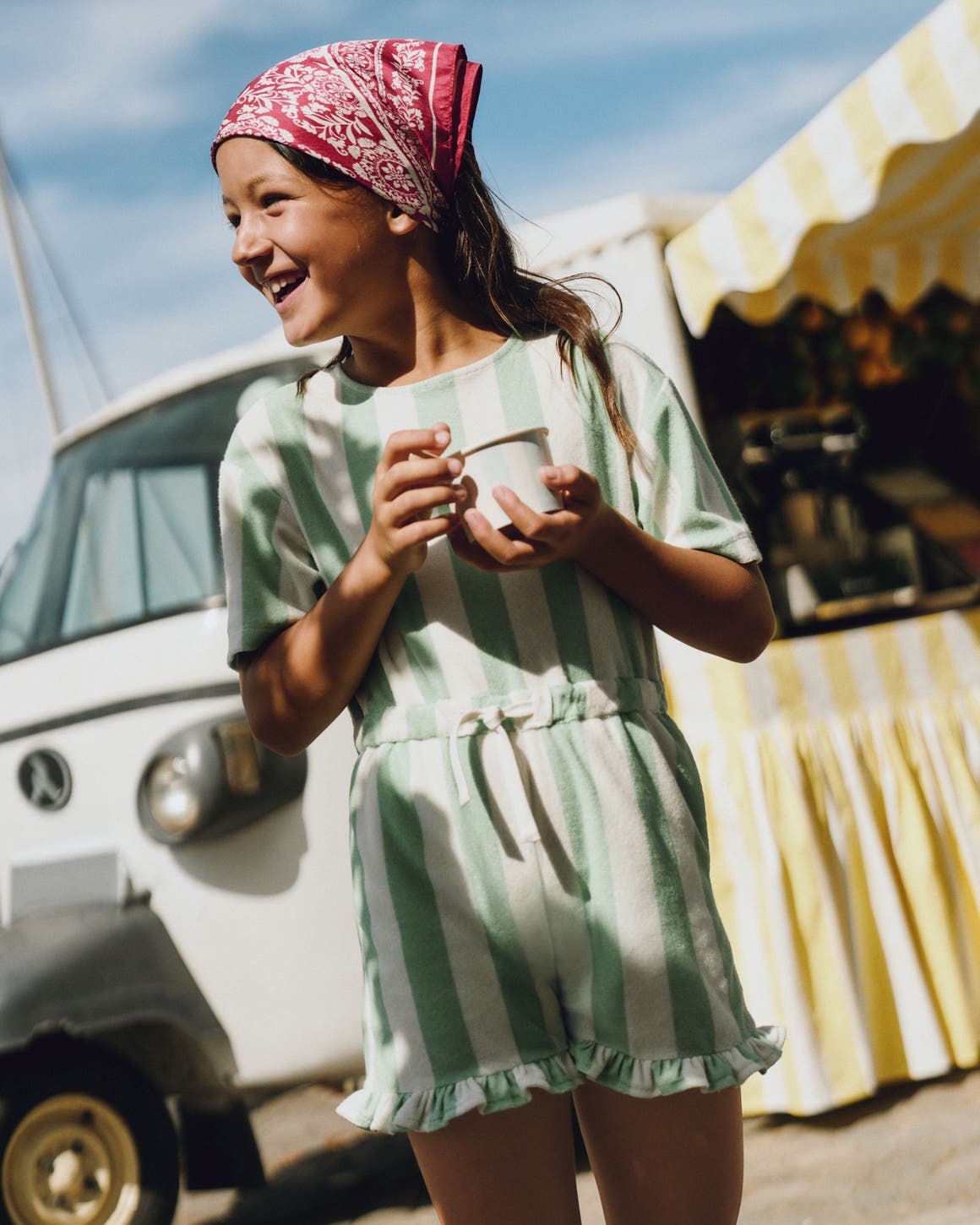 A girl wearing a striped romper from Mini Boden.