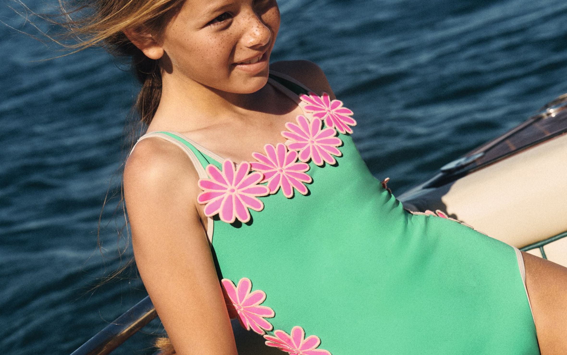A girl wearing a green Mini Boden swimsuit.
