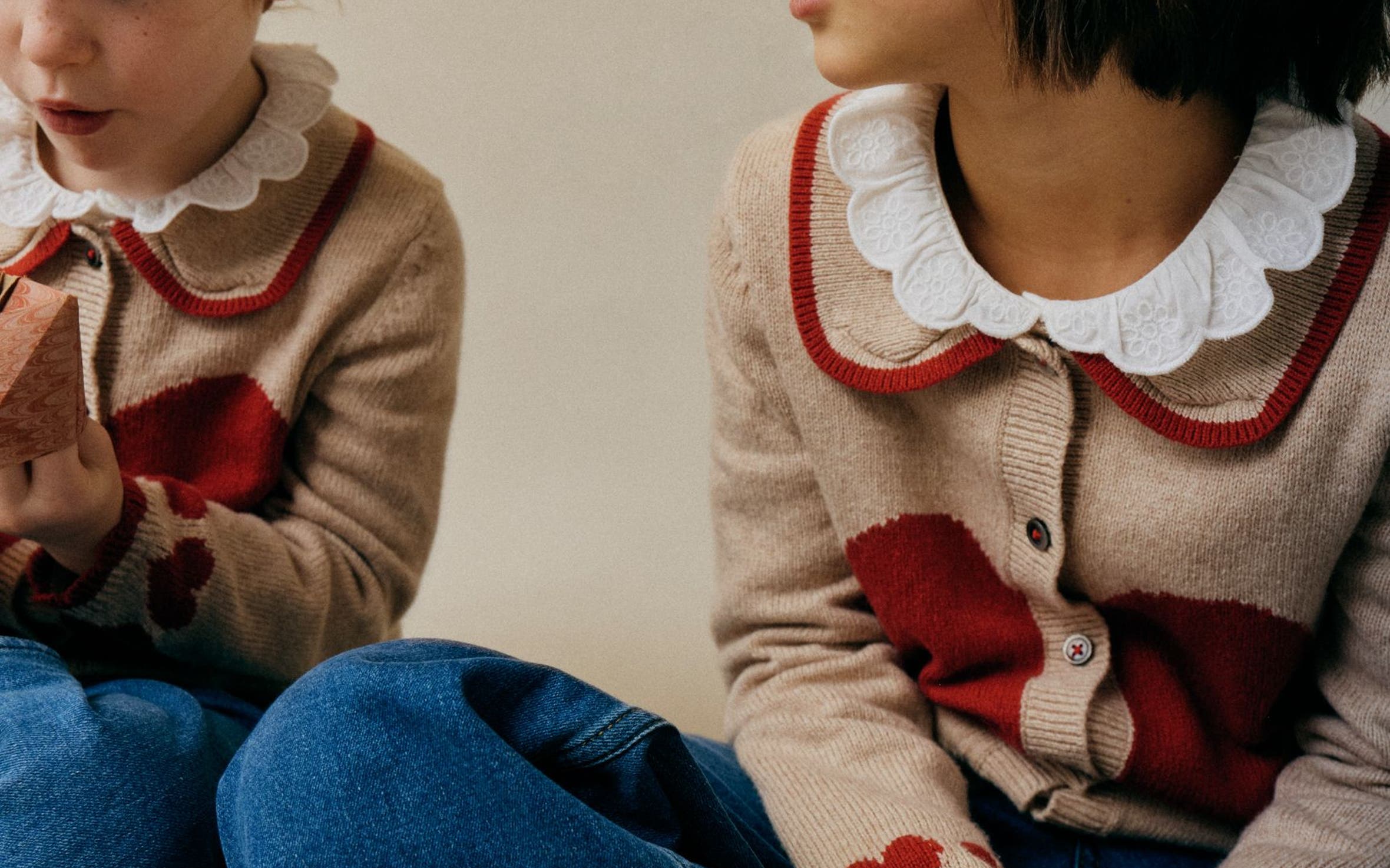 Two little girls wearing matching Mini Boden heart cardigans.