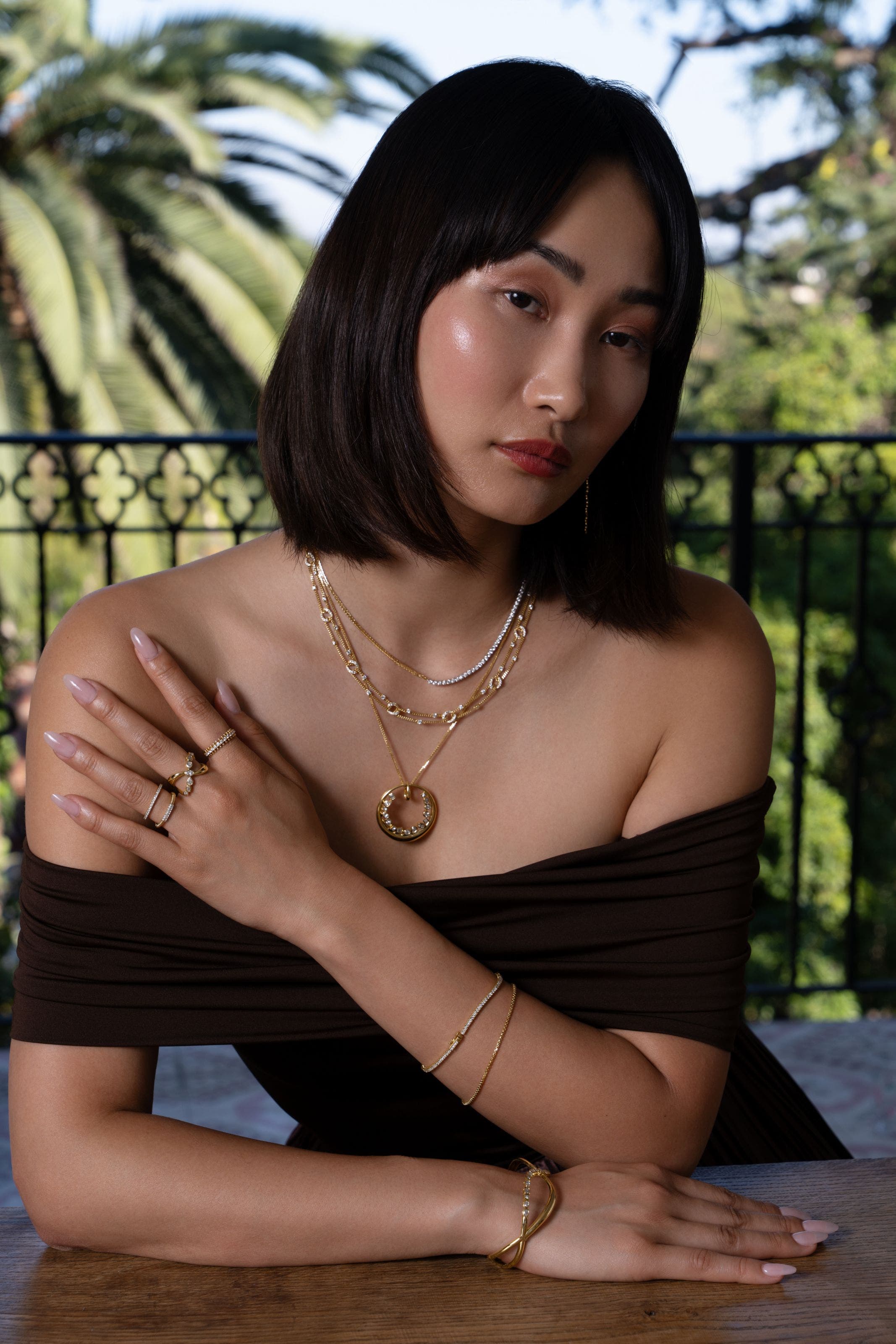 A woman wearing several gold chain necklaces, gold bracelets and rings. 