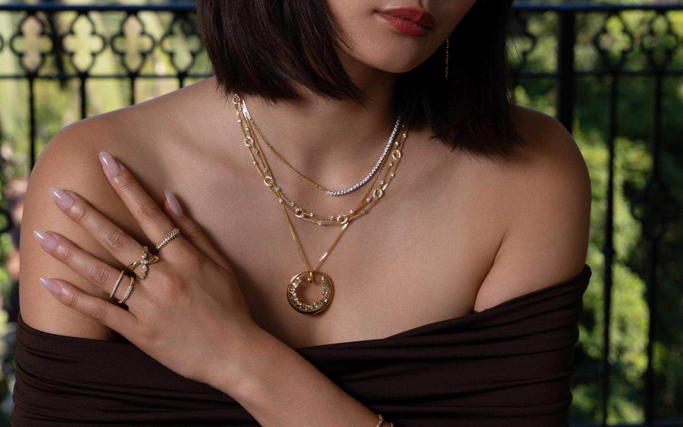 A woman wearing several gold chain necklaces, gold bracelets and rings.