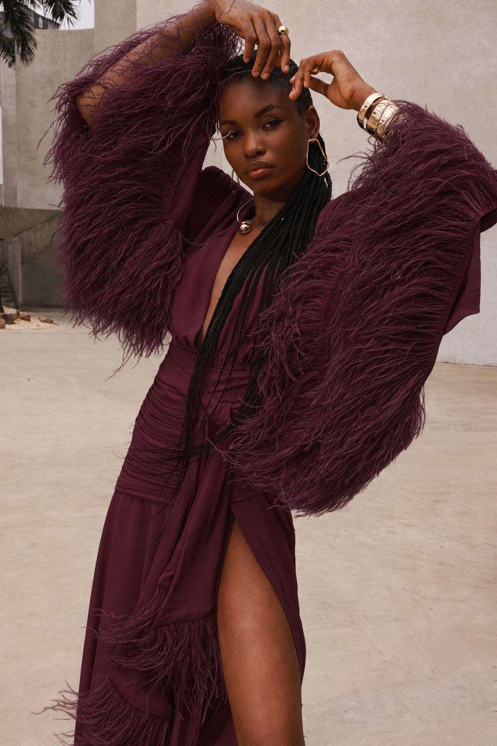 A woman wearing a burgundy gown with feather sleeves.