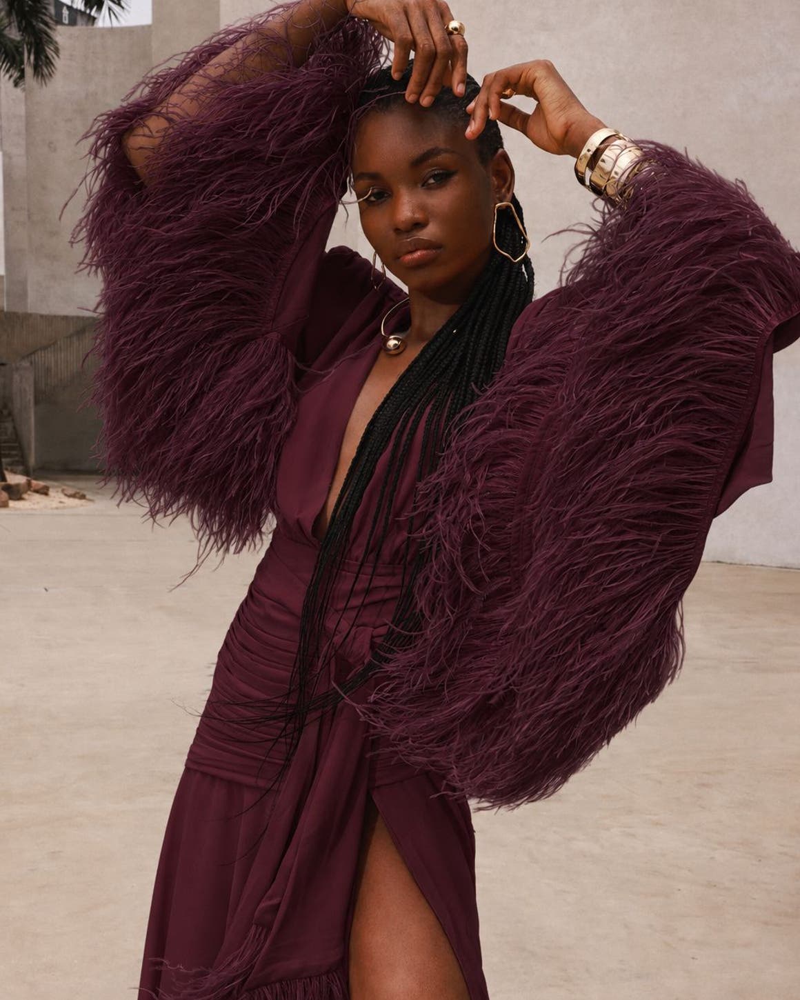 A woman wearing a burgundy long feather sleeve gown.