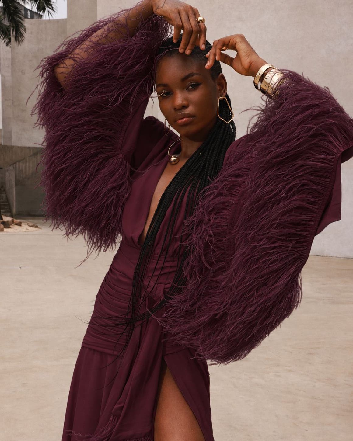 A woman wearing a burgundy long feather sleeve gown.
