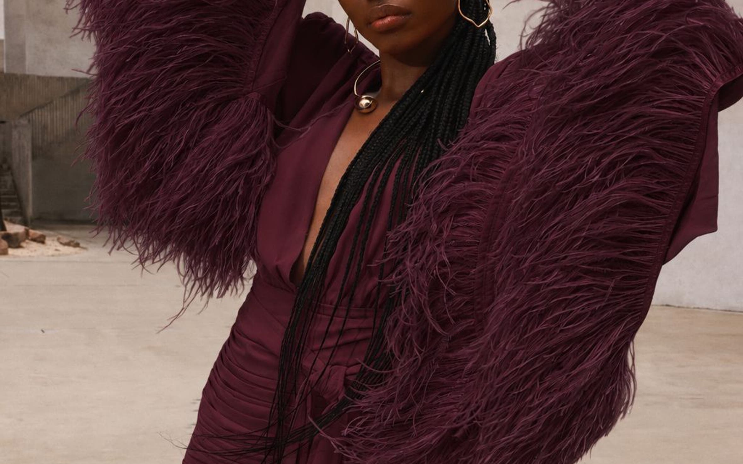A woman wearing a burgundy long feather sleeve gown.