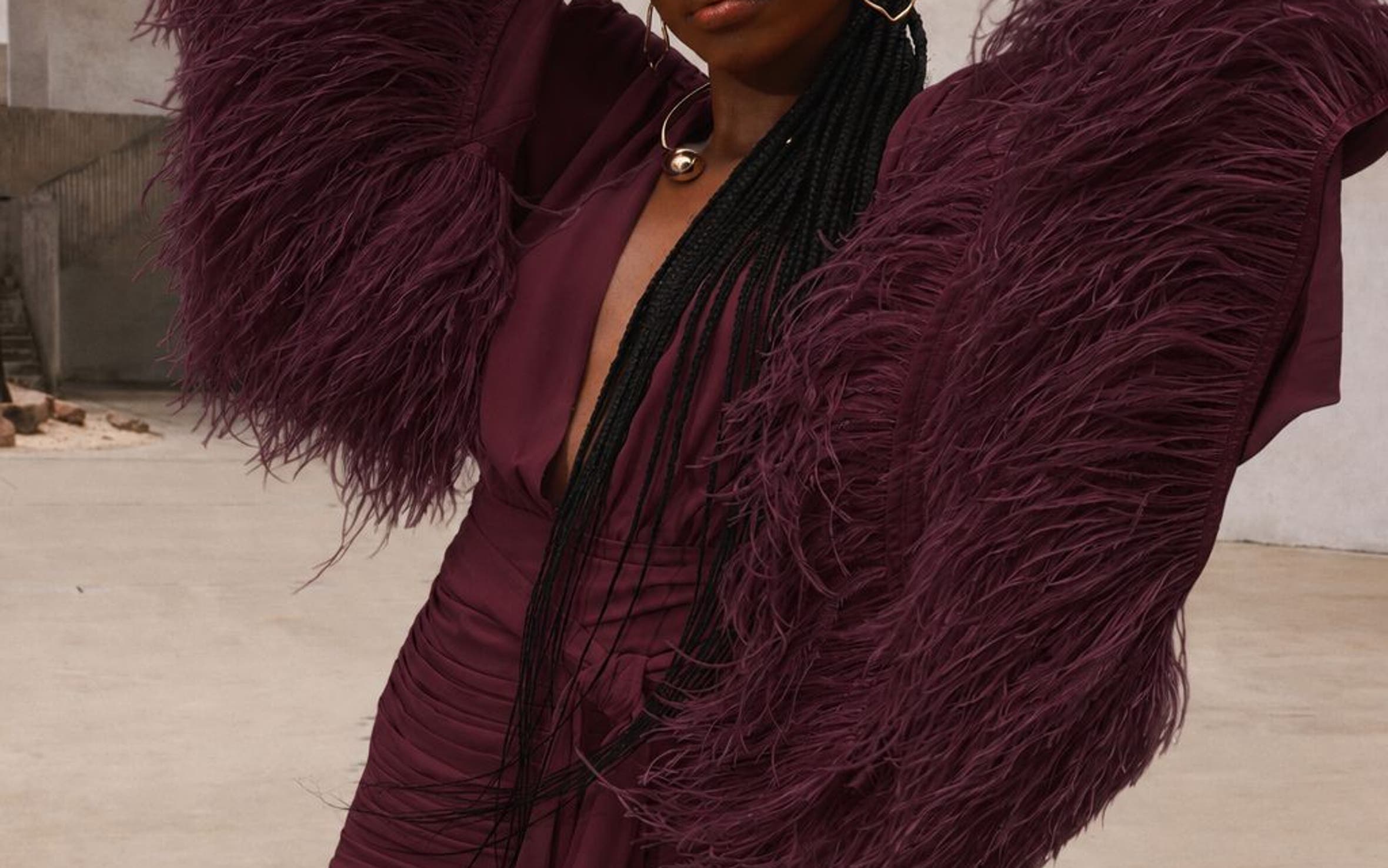 A woman wearing a burgundy long feather sleeve gown.