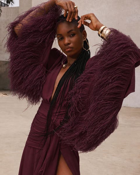 A woman wearing a burgundy gown with feather sleeves.