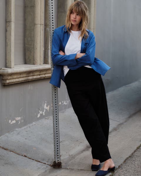 A woman wearing a white t-shirt, black pants, and a blue button-up.