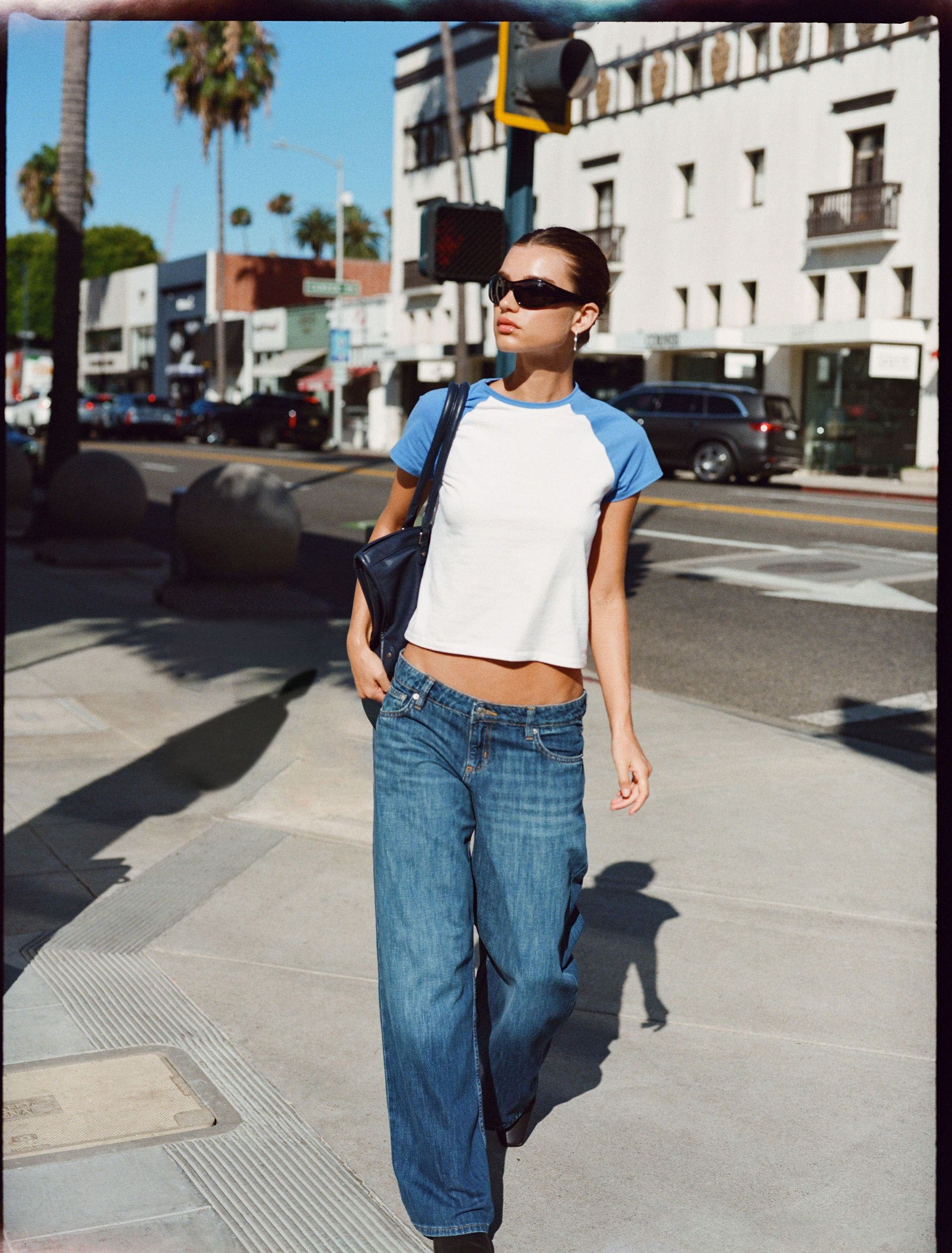 A woman wearing a baseball t-shirt and low rise jeans.
