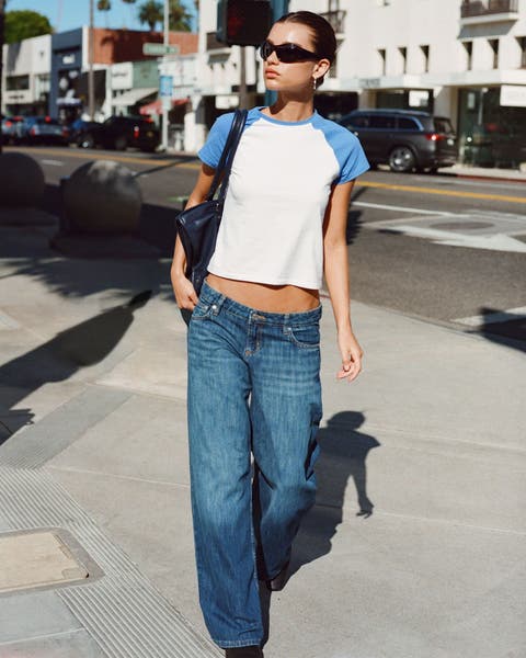 A woman wearing a baseball t-shirt and low rise jeans.