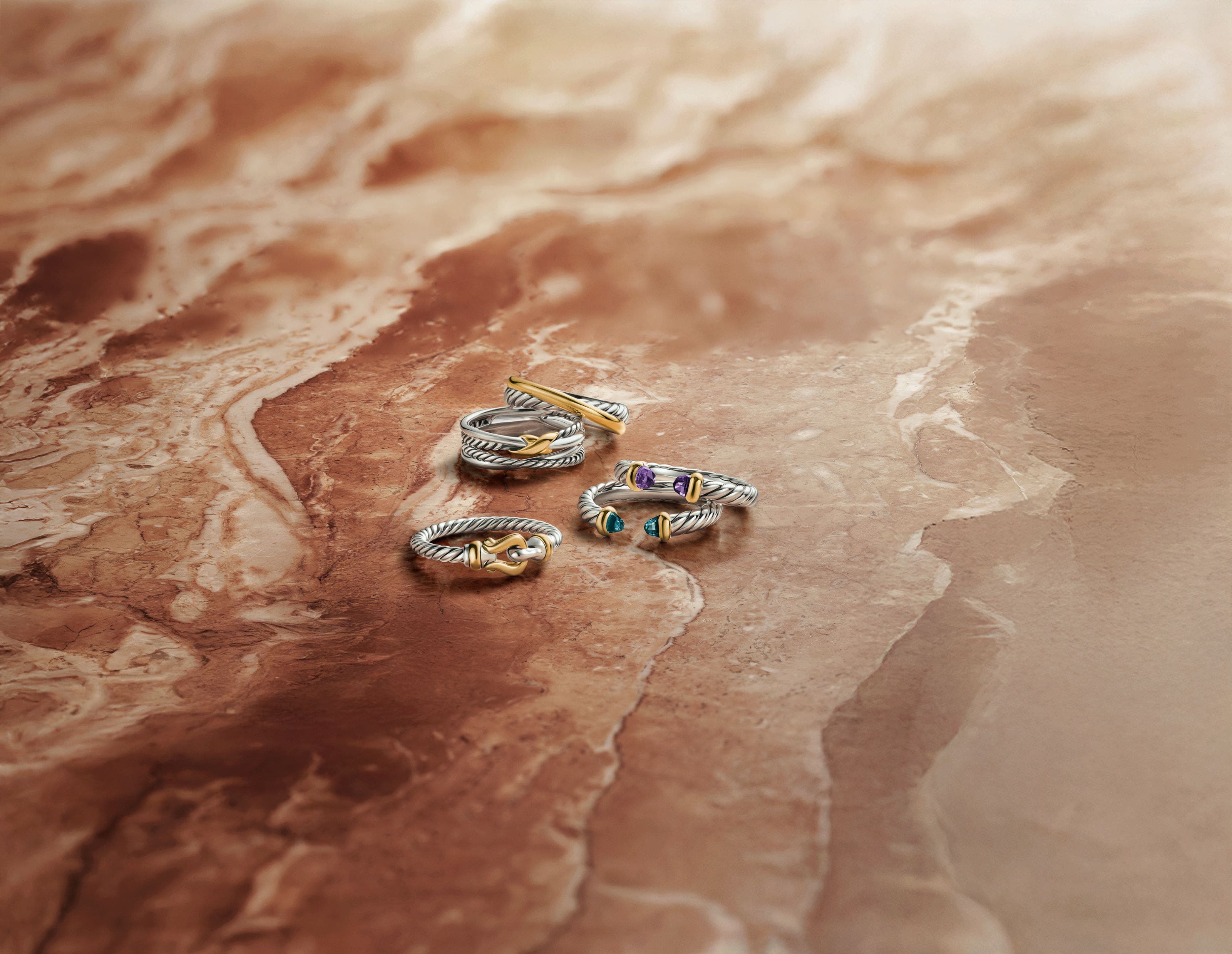 An assortment of David Yurman rings in silver and gold, some with semiprecious stones.