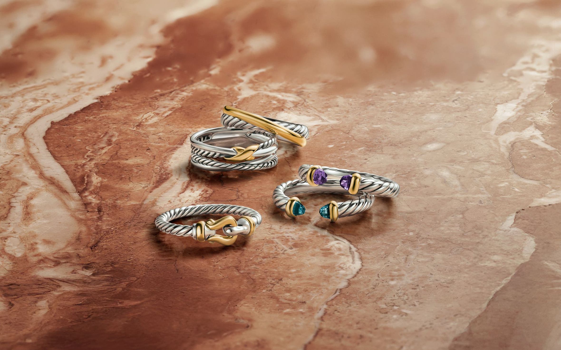 An assortment of David Yurman rings in silver and gold, some with semiprecious stones.