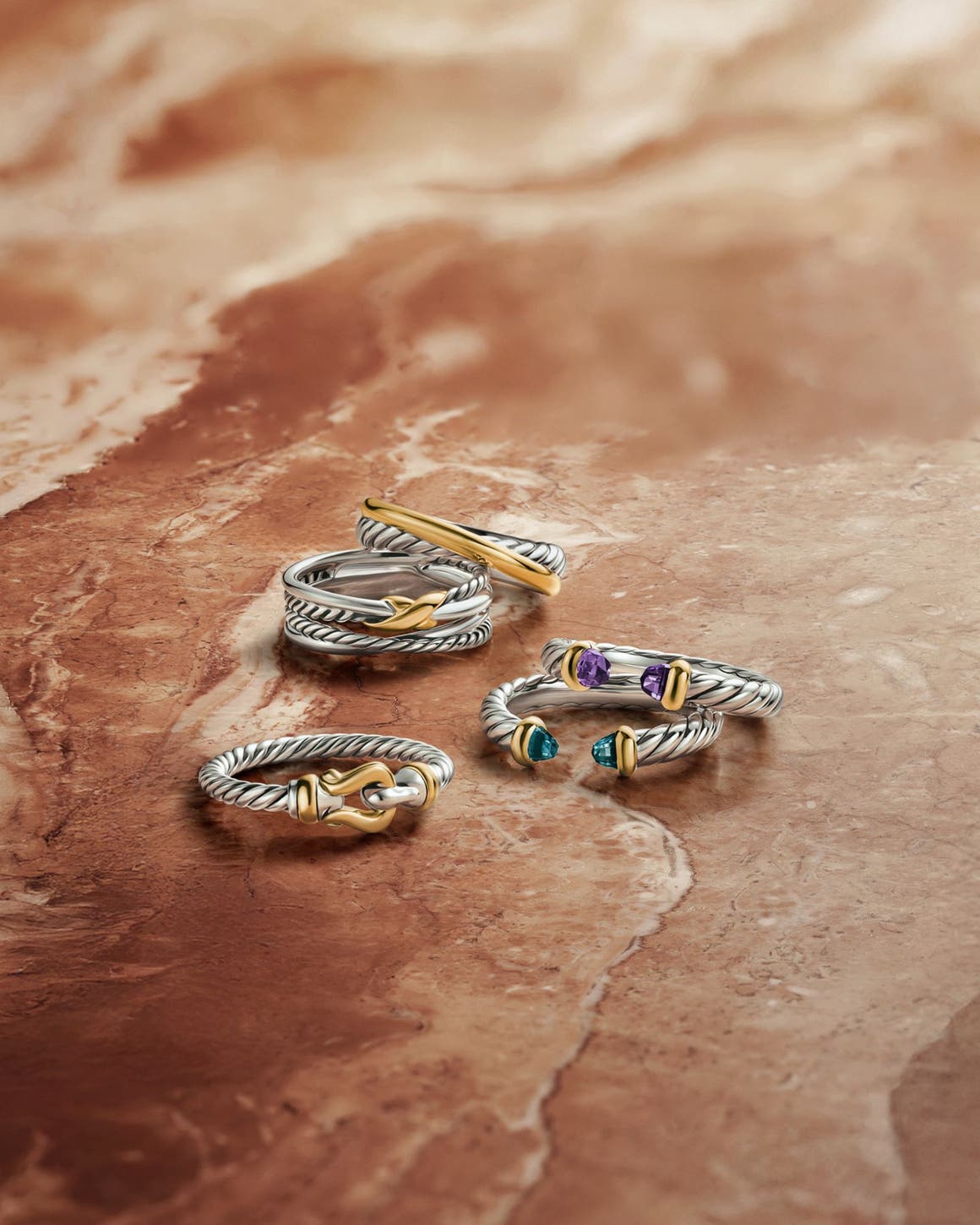 An assortment of David Yurman rings in silver and gold, some with semiprecious stones.