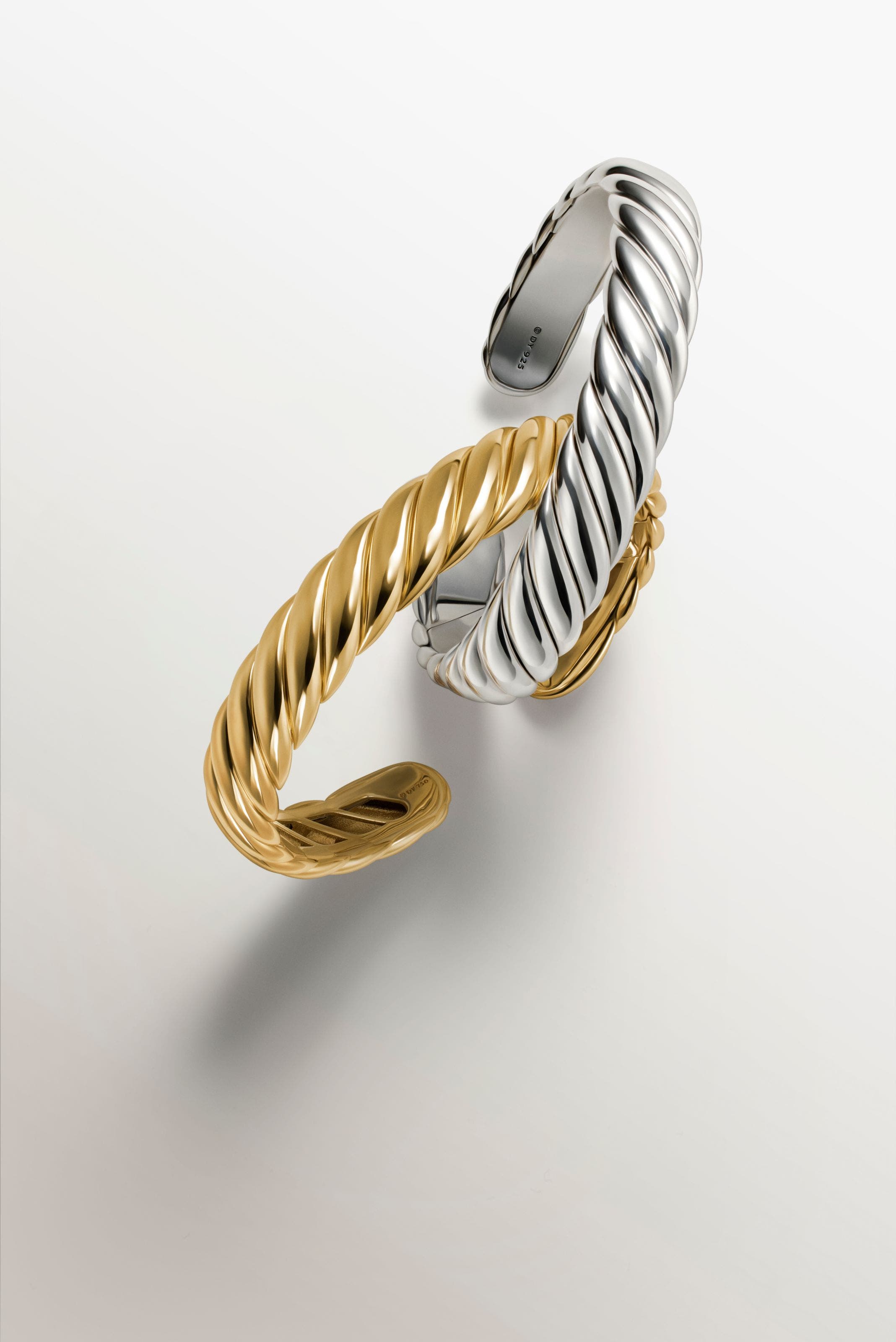 A gold and a silver cuff bracelet.