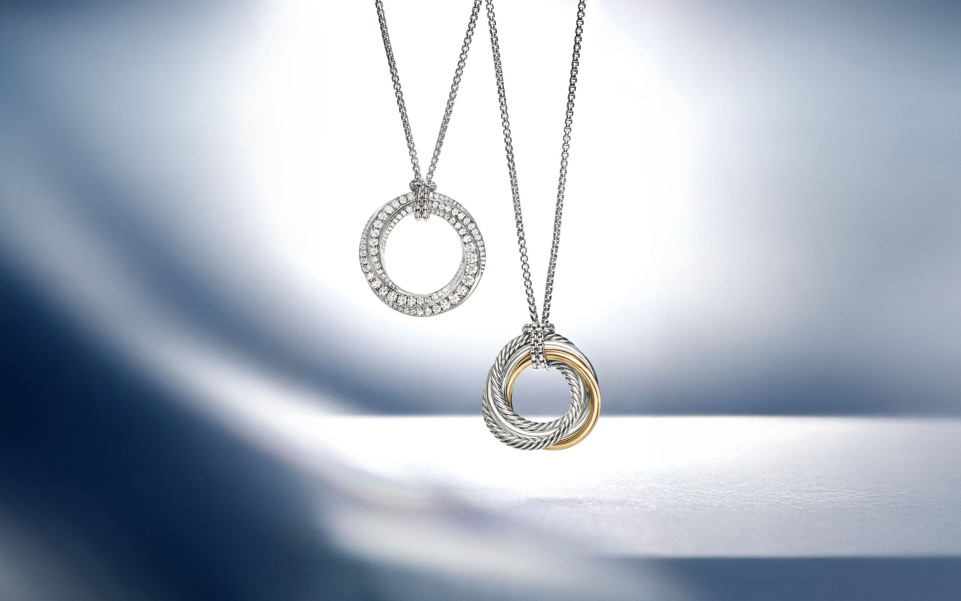 A silver necklace with diamonds and a silver and gold necklace.