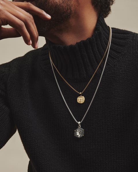 A man wearing silver and gold necklaces.