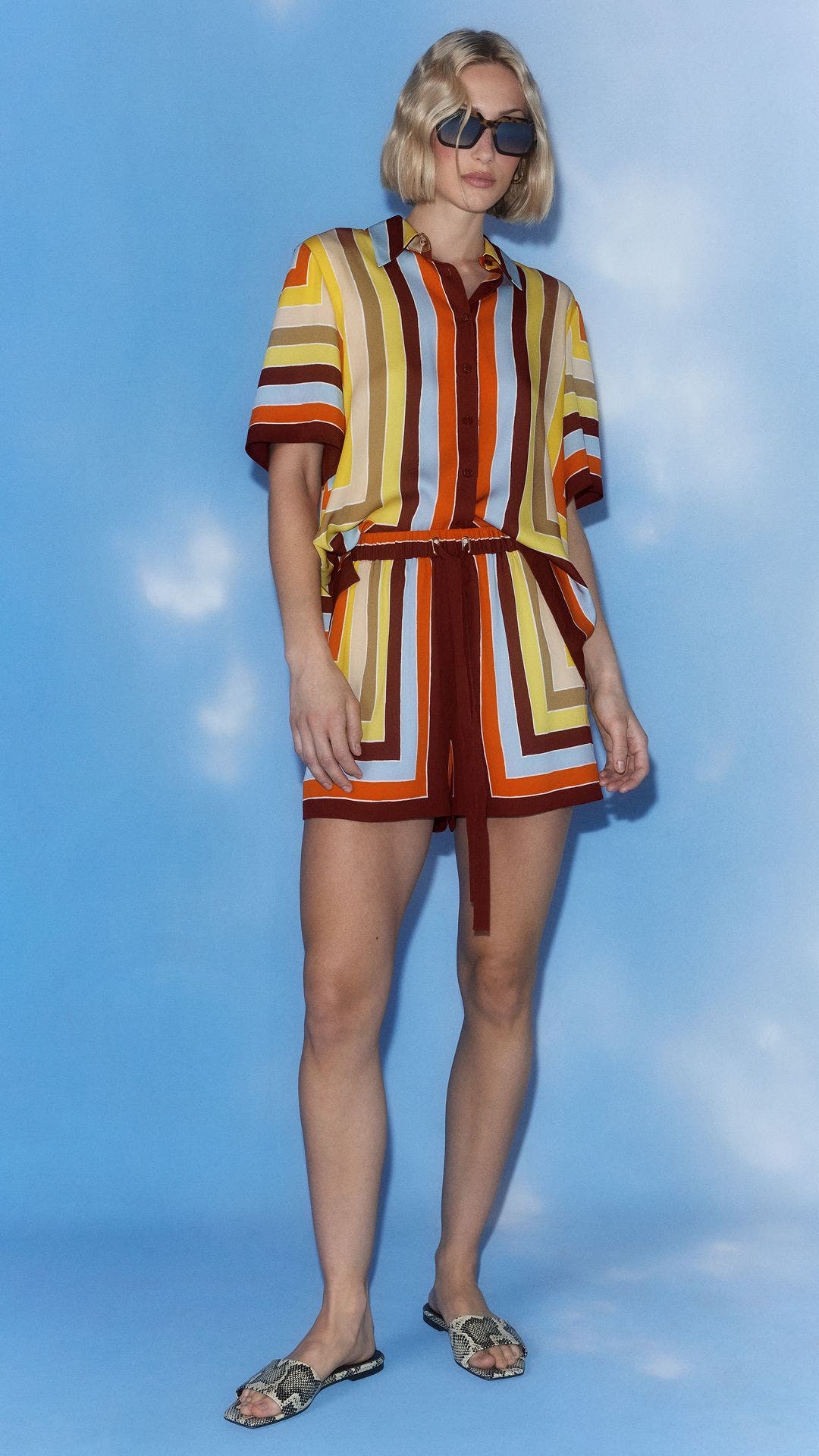 A woman wearing a matching striped silk top and shorts.