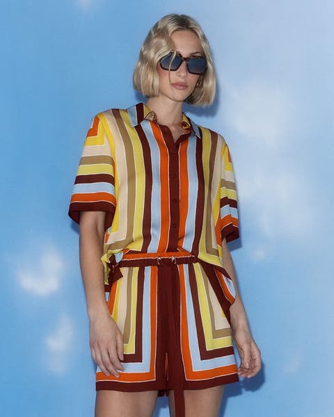 A woman wearing a matching striped silk top and shorts.