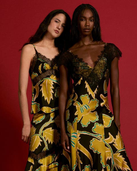 Two women wearing matching yellow and black printed dresses.