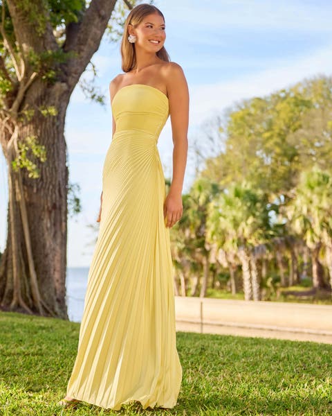A woman wearing a yellow strapless maxi dress.