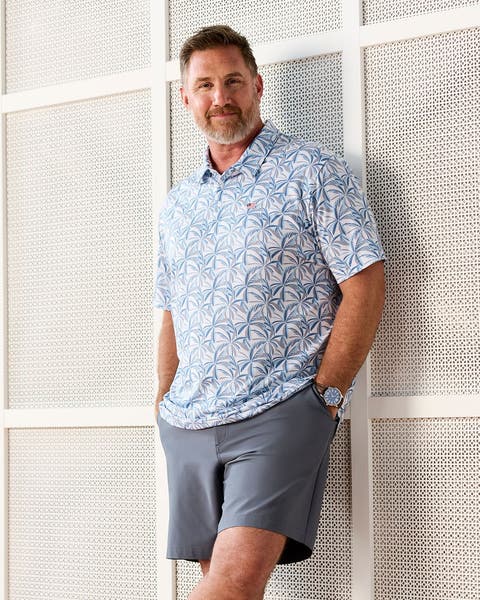 Man wearing floral print polo and grey shorts.