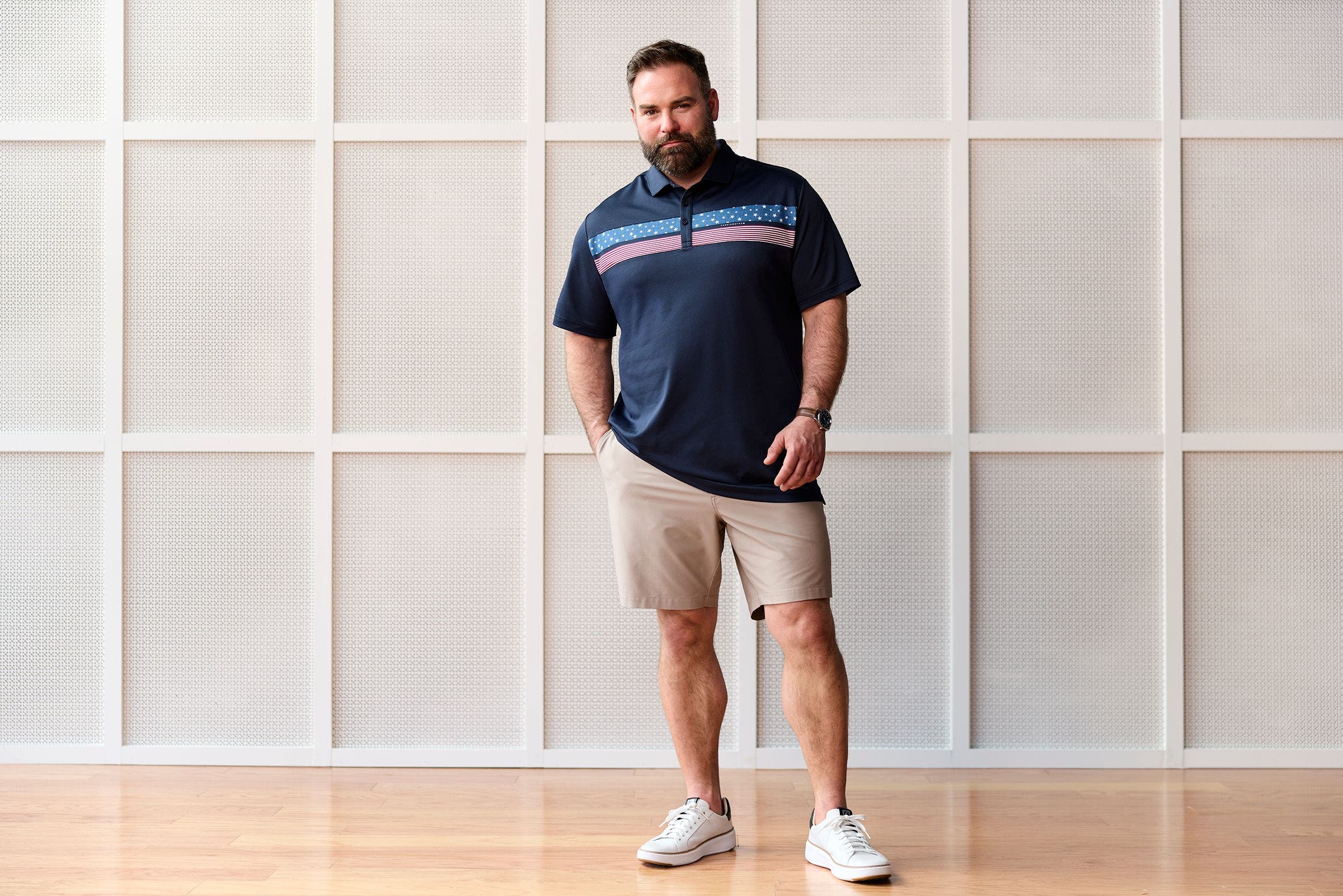 Man wearing navy polo, chino shorts and white sneakers.