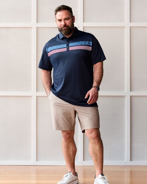 Man wearing navy polo, chino shorts and white sneakers.
