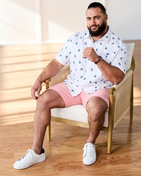 Man wearing a button-up shirt and pink shorts.