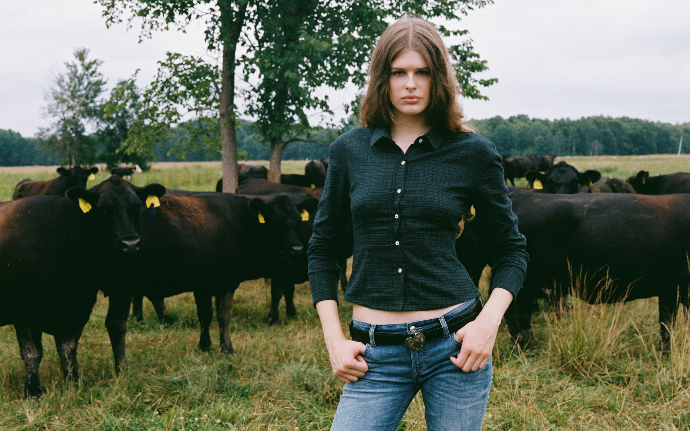 A woman wearing a button up shirt and a pair of low-rise denim.