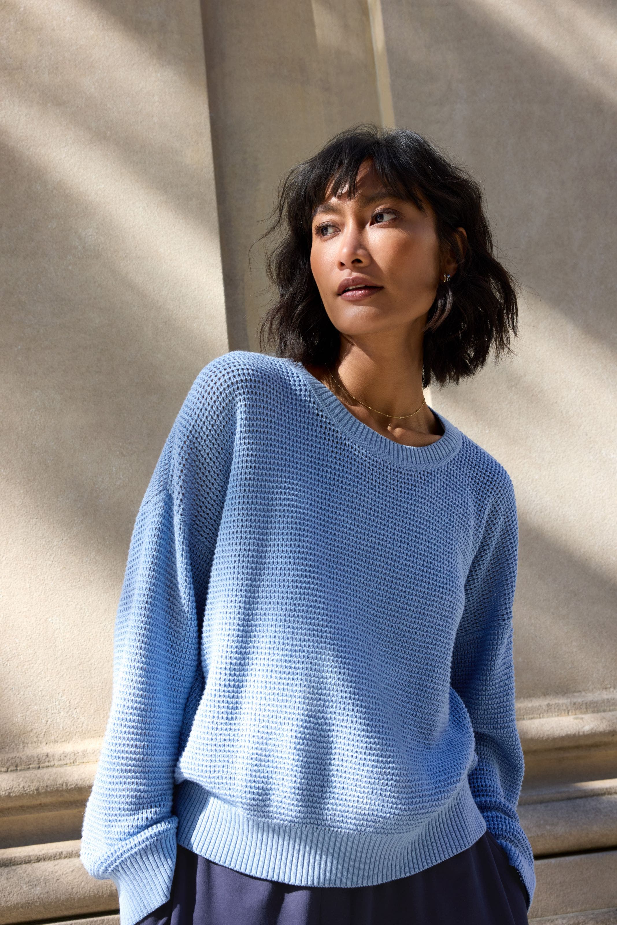 Woman wearing blue lightweight cotton sweater. 