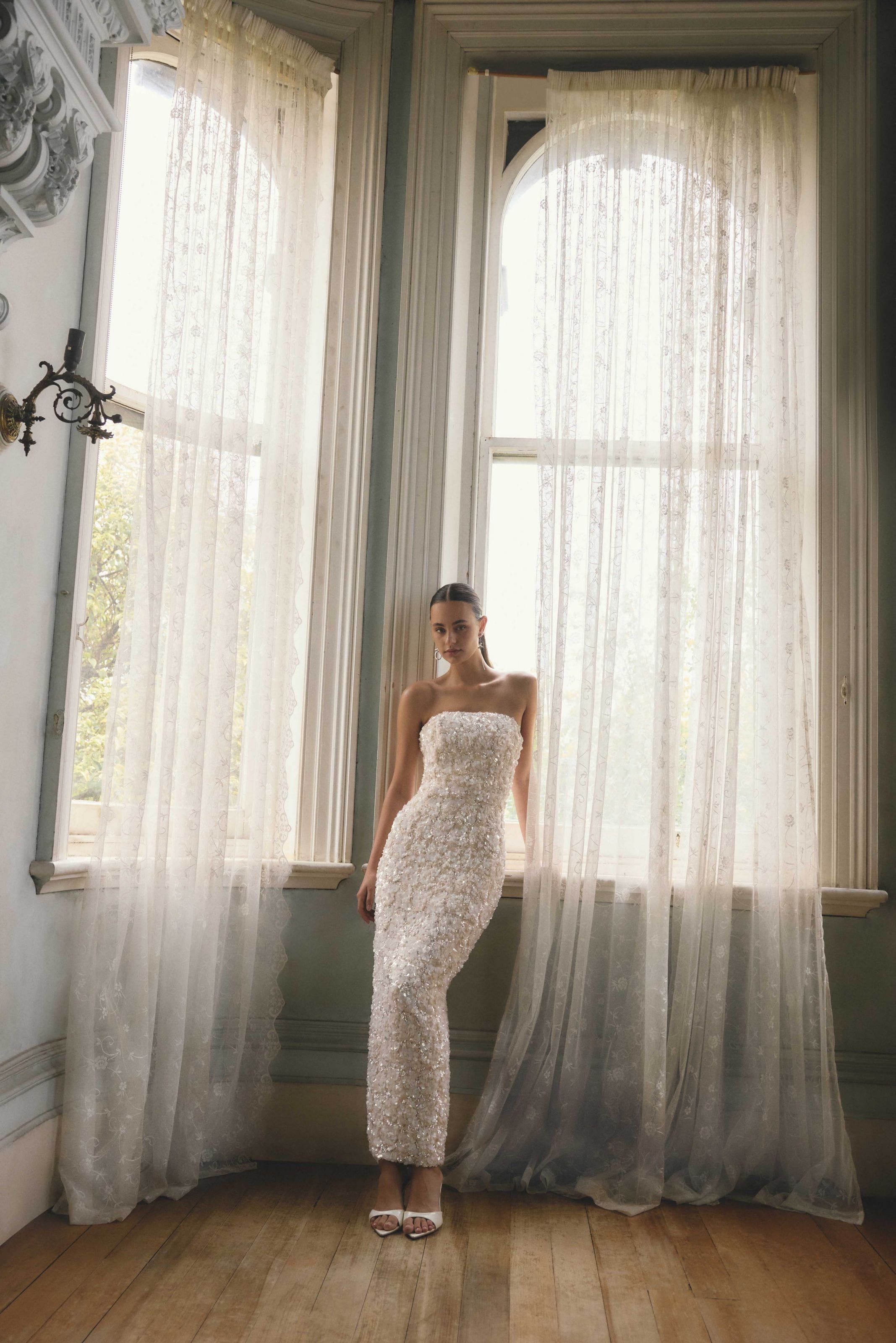 A woman wearing a beaded strapless white bridal dress. 
