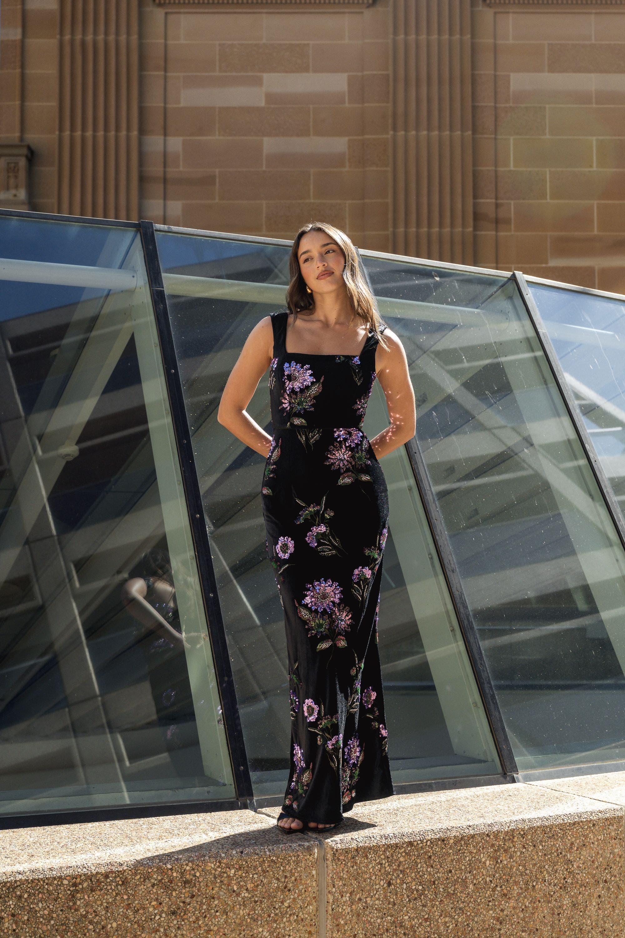 A woman wearing a black dress with purple flower design.