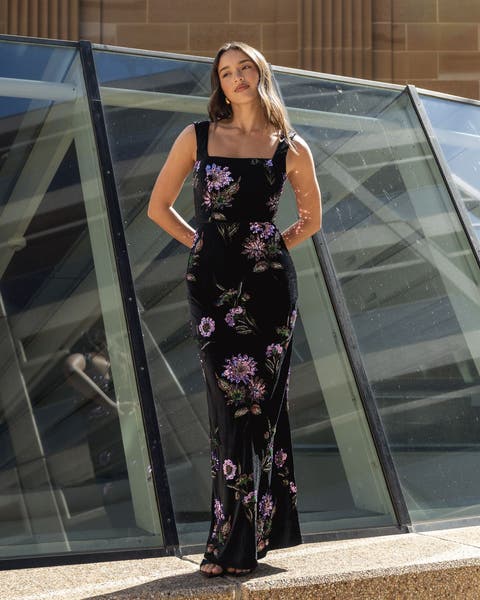 A woman wearing a black dress with purple flower design.