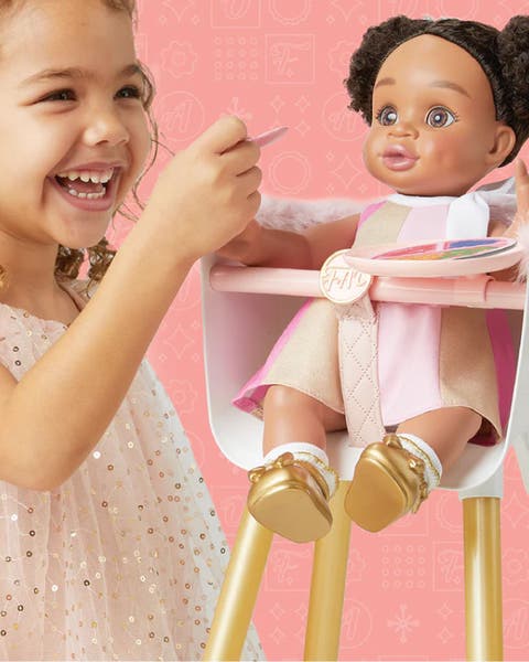 A girl playing with a doll in a high chair.
