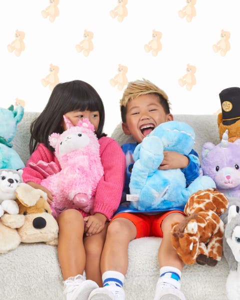 A boy and girl surrounded by plush toys.