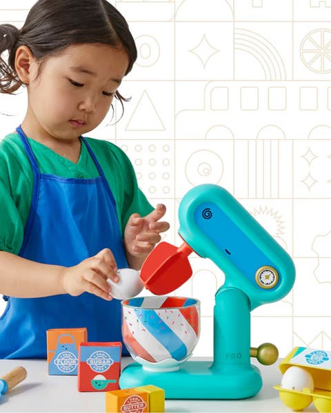 A girl playing with a pretend stand mixer.