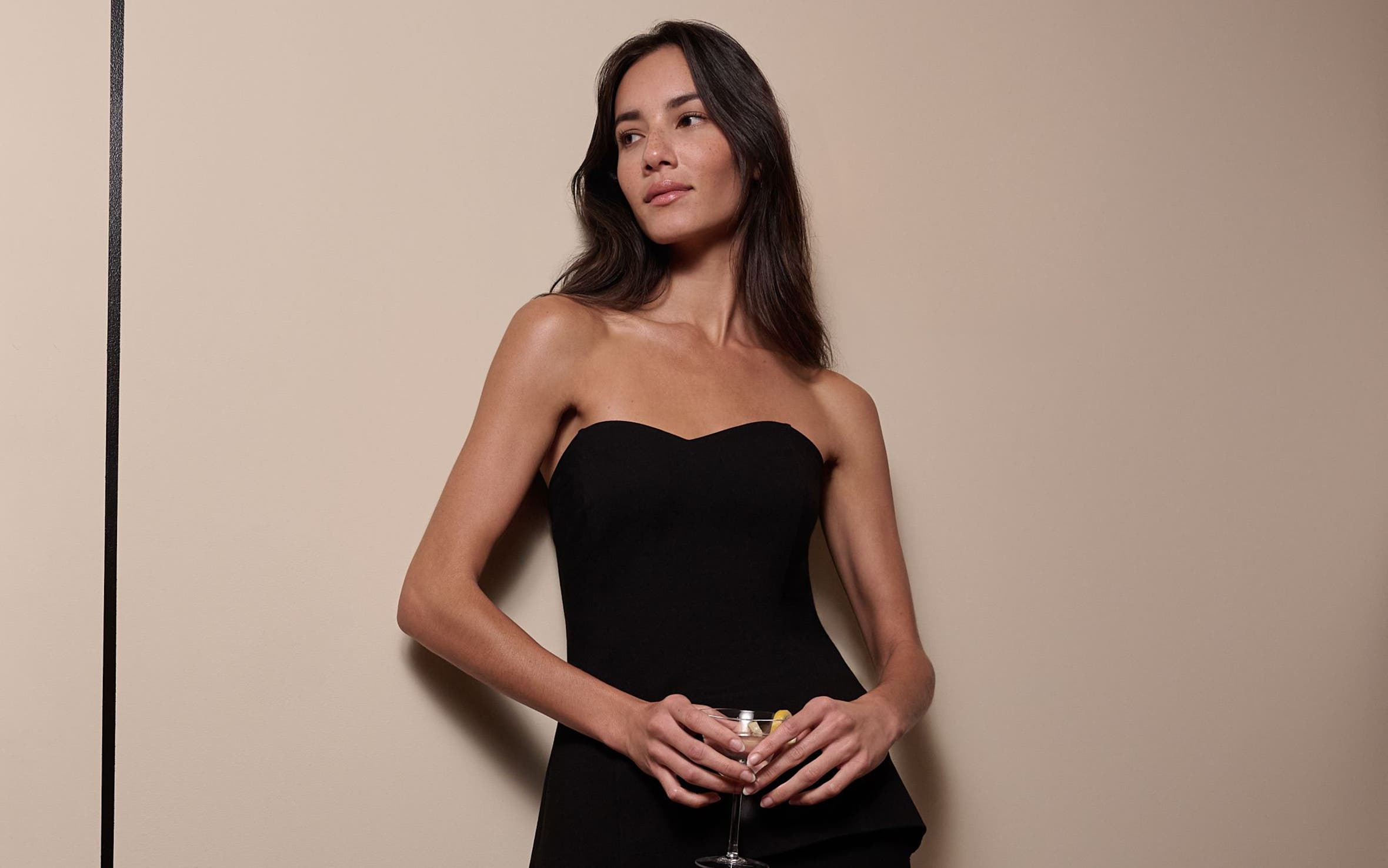 A woman wearing a black corset top and black pants.