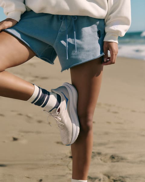 A woman wearing a sweatshirt, shorts, sneakers and socks.