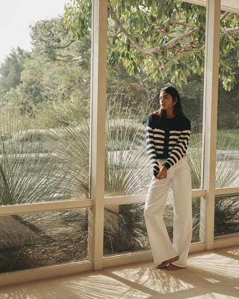 Woman wearing a striped FRAME sweater and white denim.