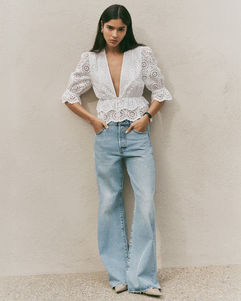Woman wearing white FRAME top and light wash jeans.