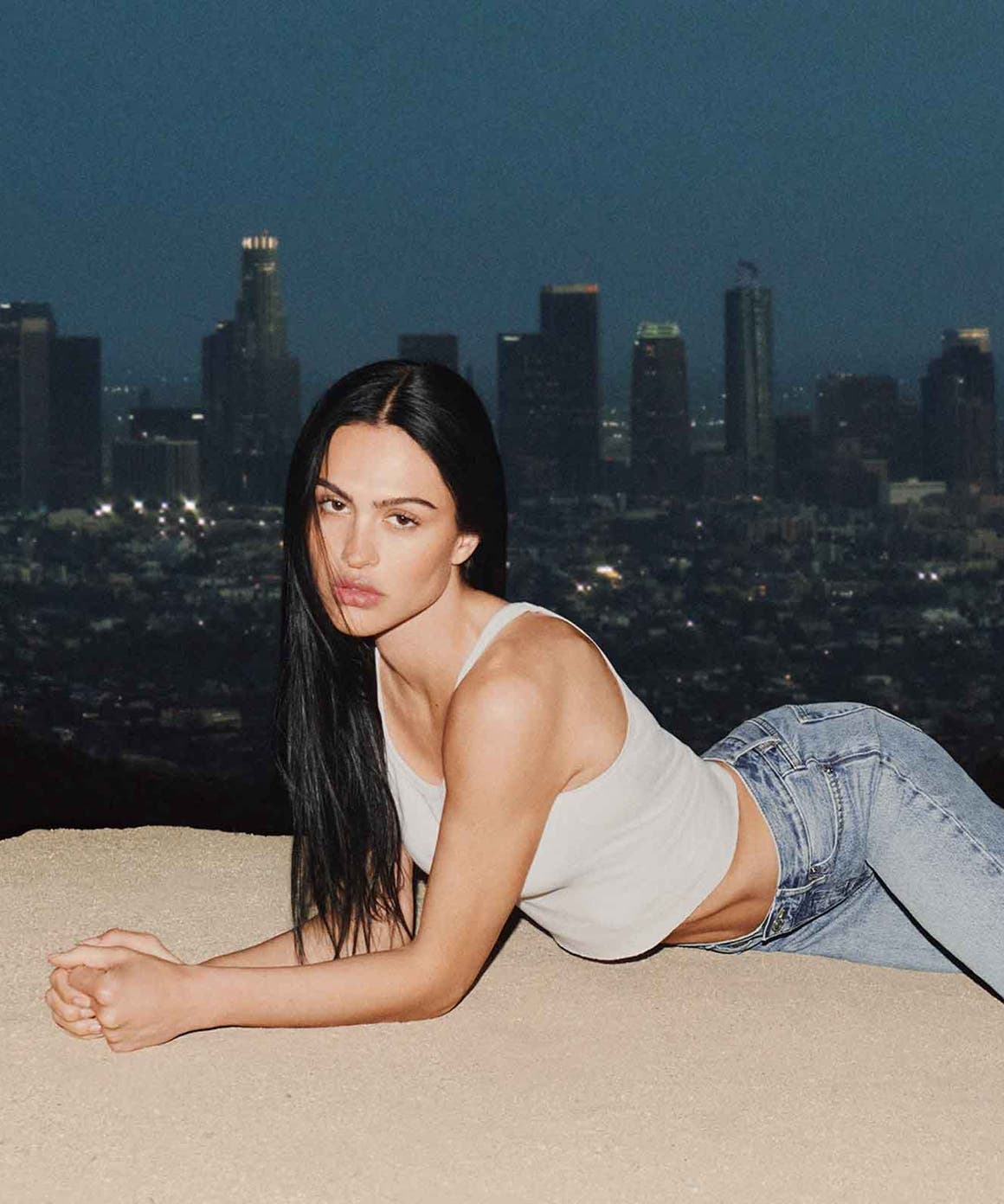 Woman wearing FRAME denim laying on sand.