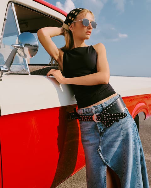 A woman wearing a tank top and denim skirt.