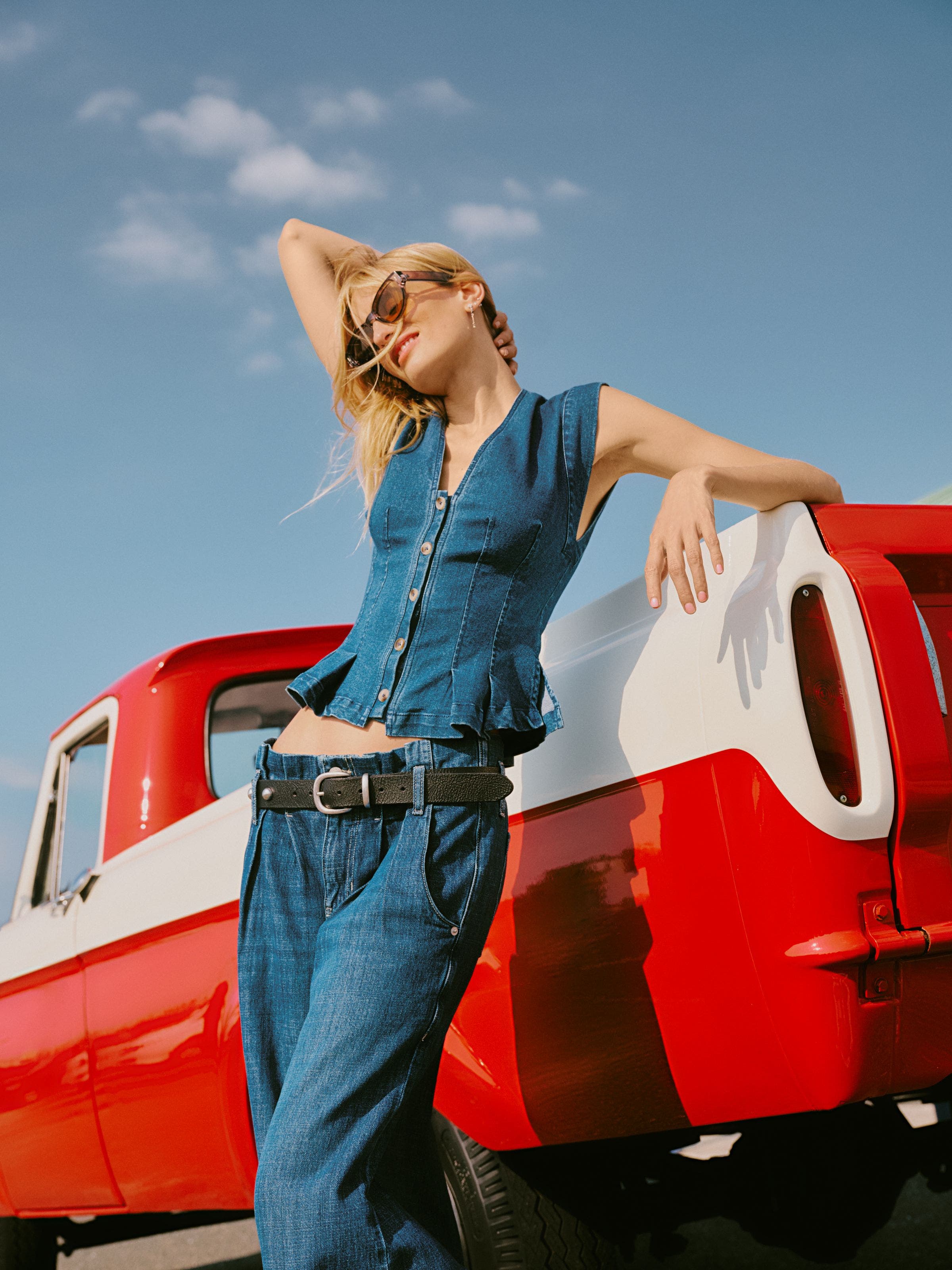 A woman wearing a sleeveless button-up denim top.