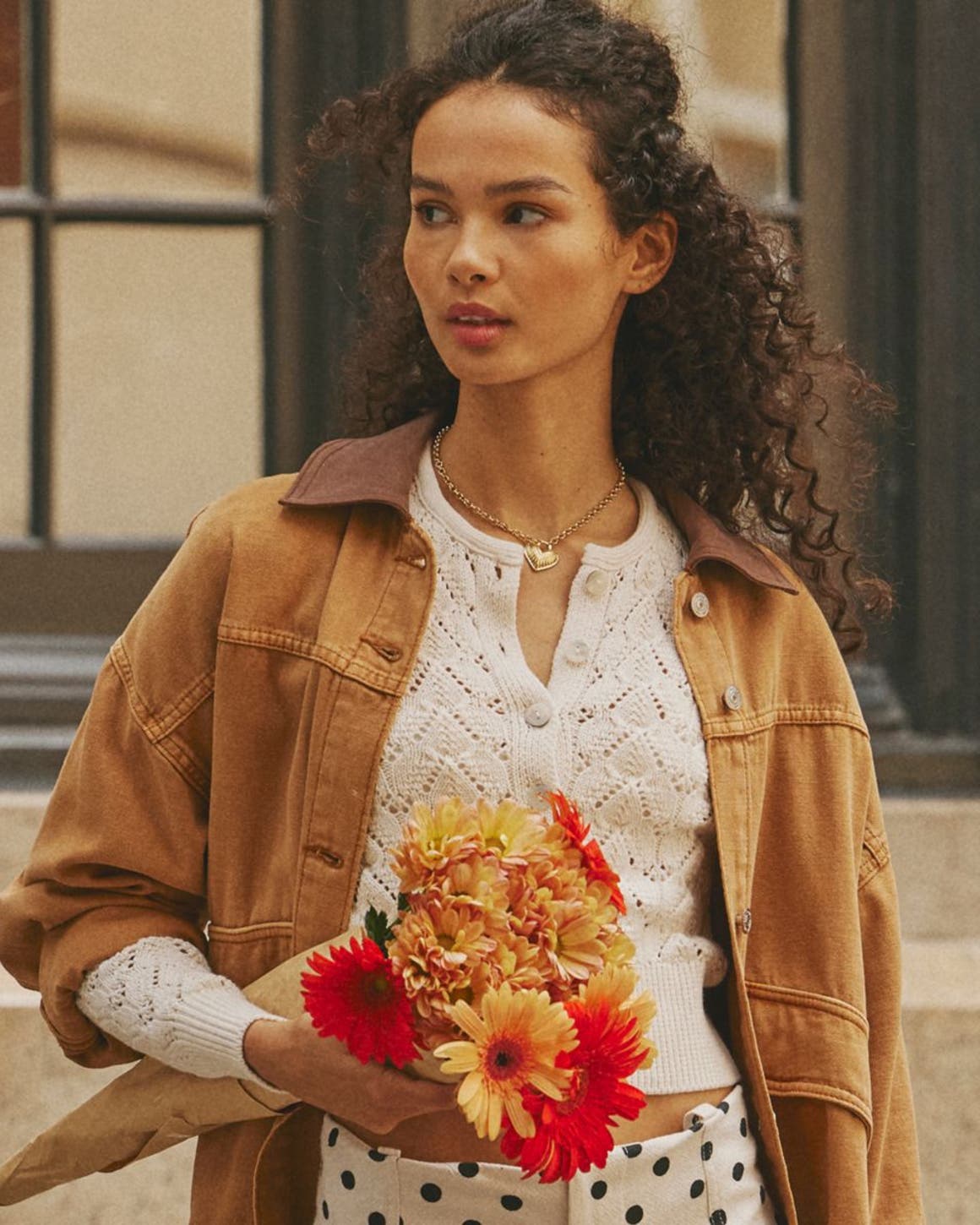 Free People model wearing utility jacket, white top, and polka dot skirt