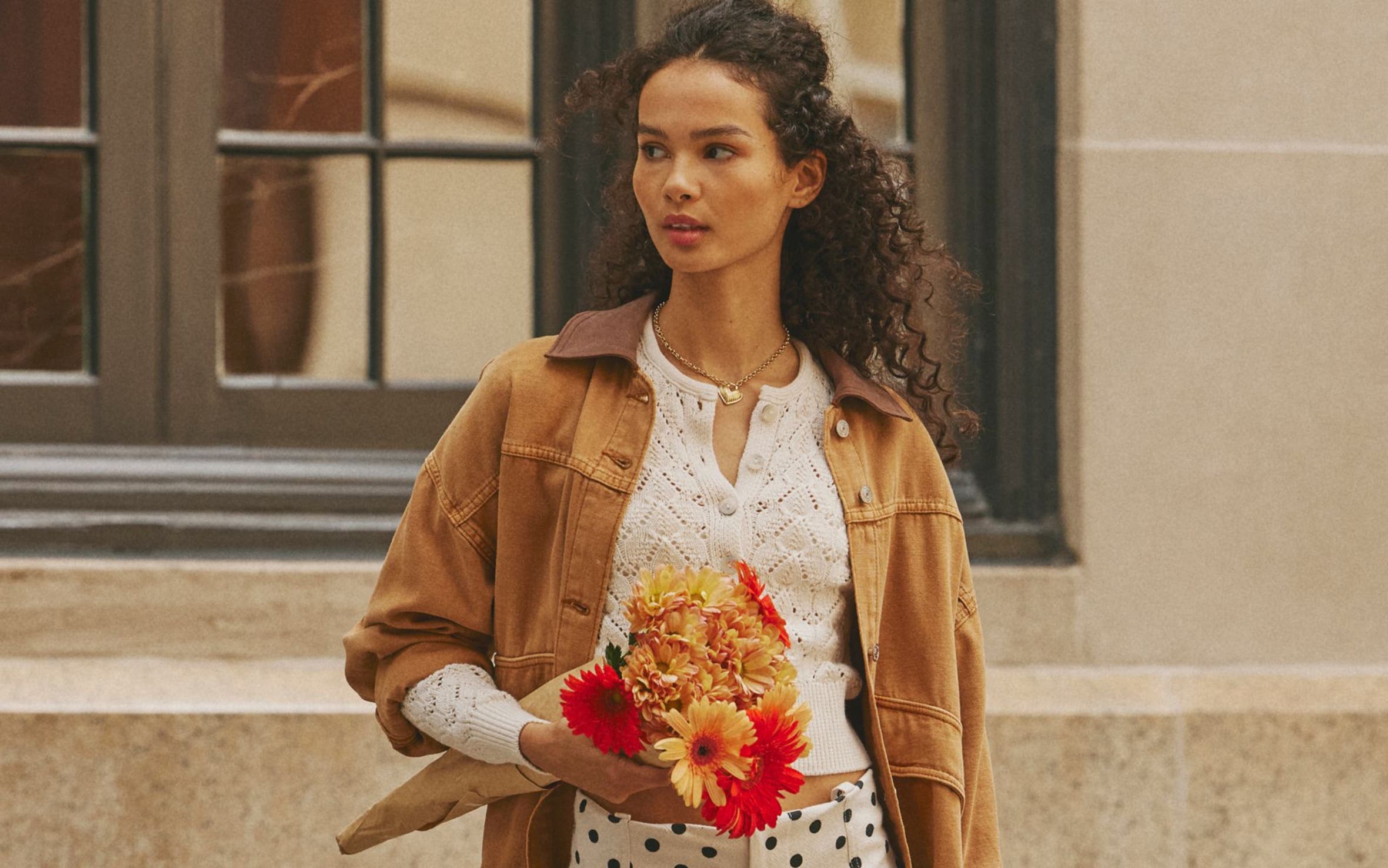 Free People model wearing utility jacket, white top, and polka dot skirt