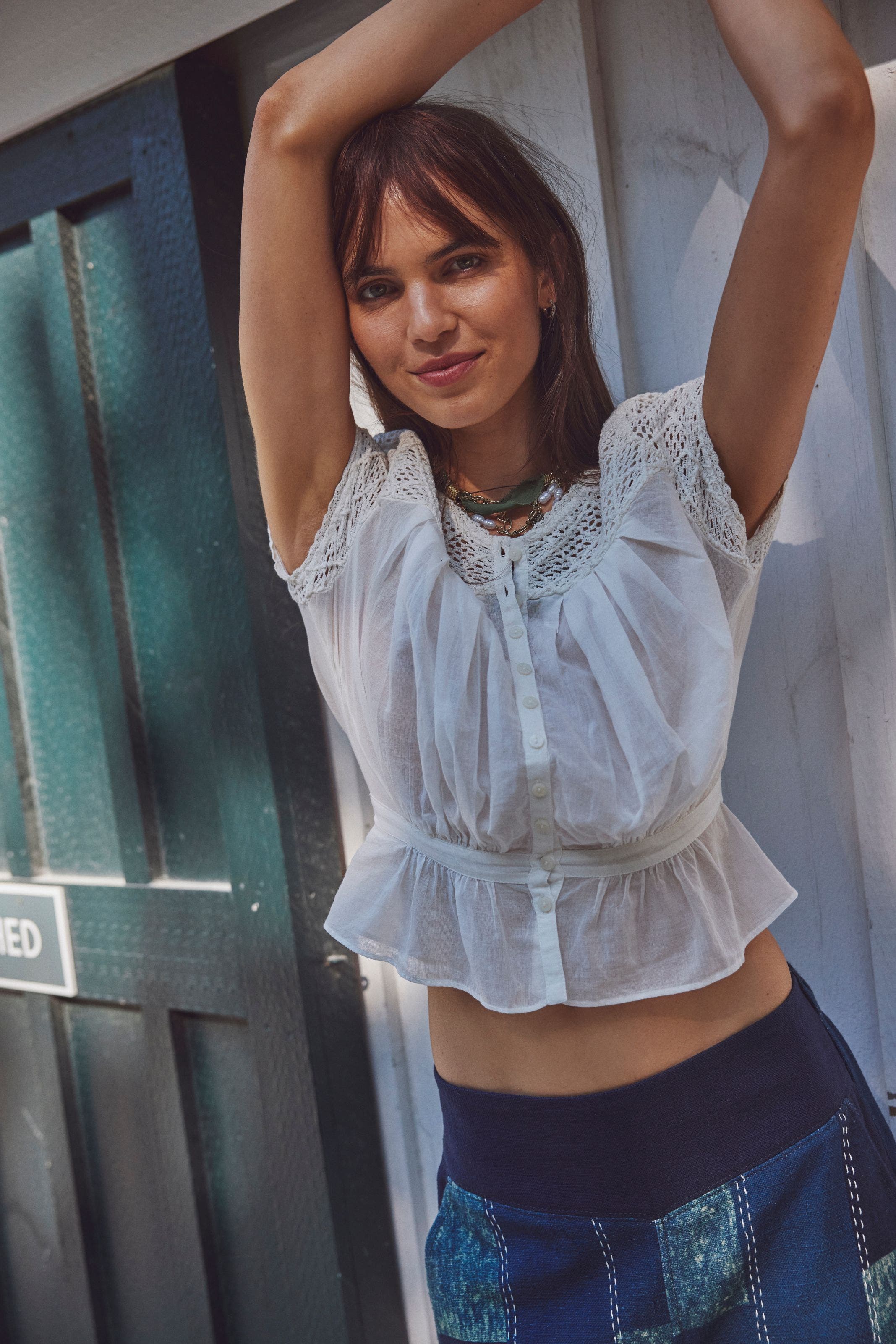 A woman wearing a lace-trimmed white top.