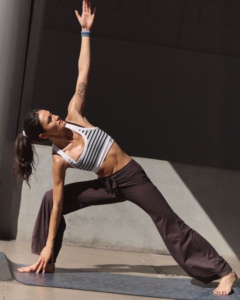 Woman wearing a striped bra and brown FP Movement pants.