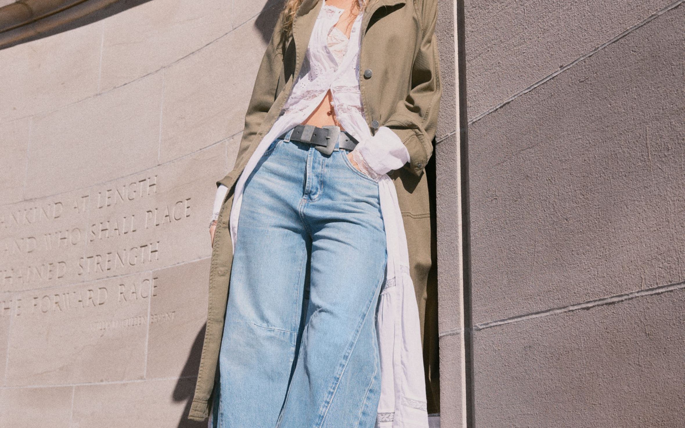 A woman wearing a Free People beret, dress, trench coat and jeans.
